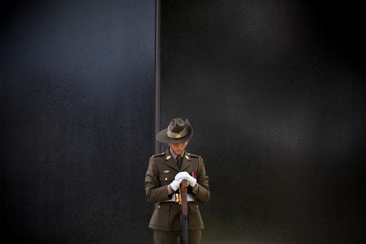 A female soldier standing in front of black polished stone which is a part of the Australian Peacekeeping Memorial.