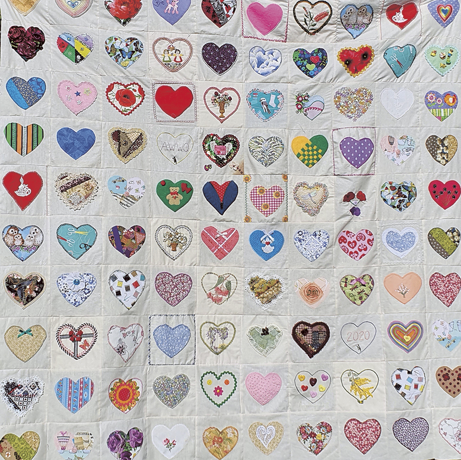 Close-up image of a quilt covered in a colourful love heart pattern