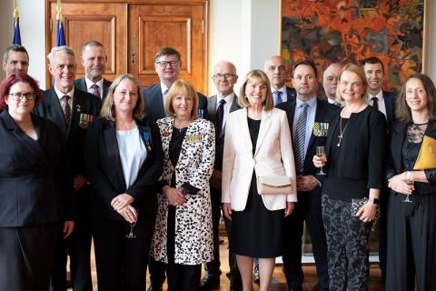 Group of about 15 people posing for camera in large, nicely decorated room.