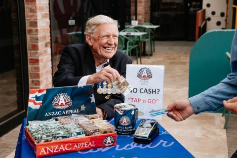 Elderly man wearing medals taking donations