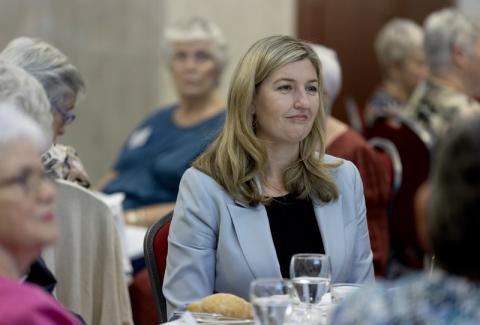 Smiling woman sitting at dinner table at dinner event