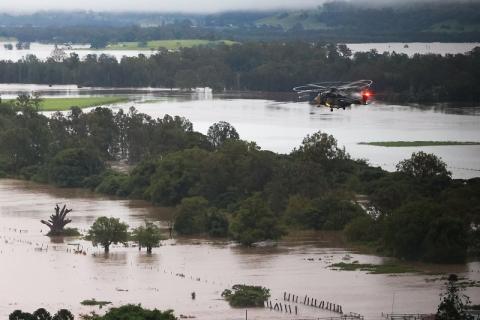 Army helicopter flying over flooded bushland