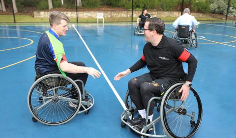 Minister for Veterans' Affairs Matt Keogh is trying out wheelchair rugby league, he is about to shake hands with a participant